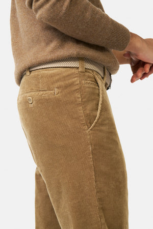 Brown corduroy pants worn by a person on a grey background