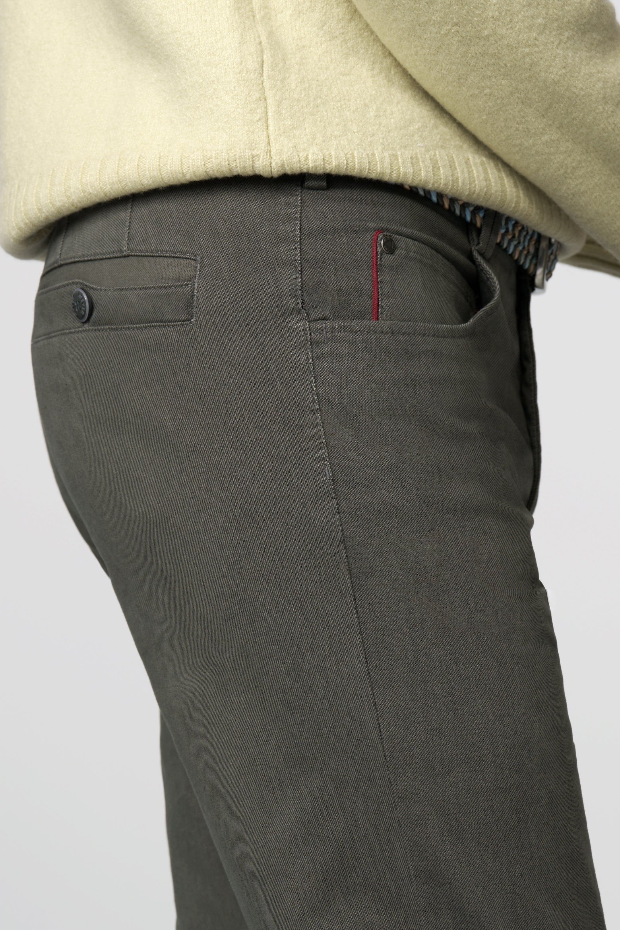 Dark gray pants with a beige sweater on a light gray background