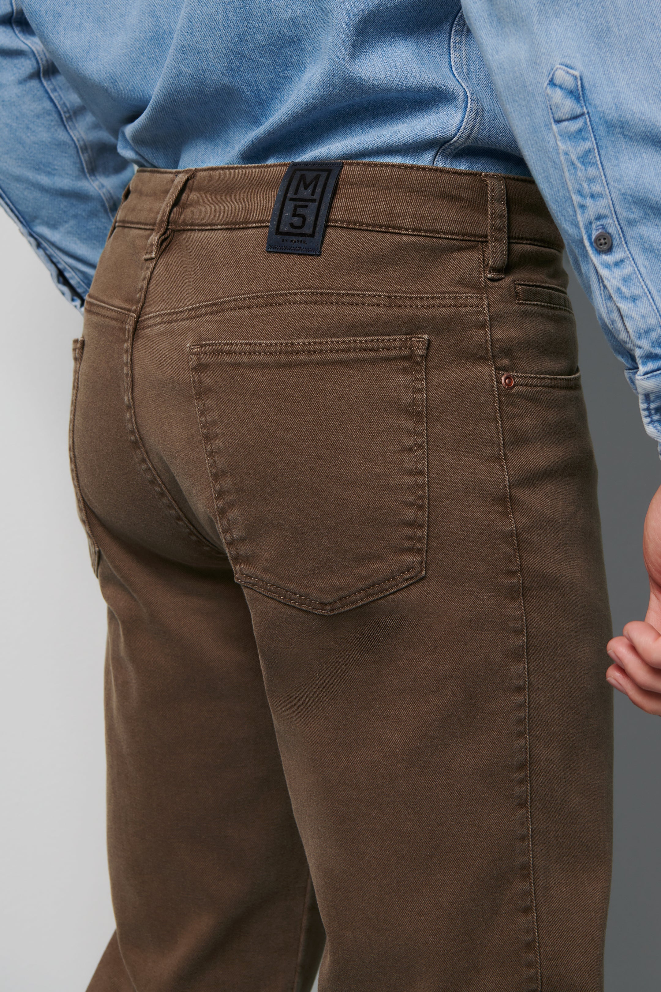 Brown pants with a visible brand label worn by a person in a blue shirt.